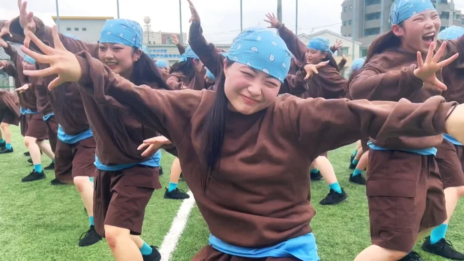 若者たちが、人工芝のグラウンドで笑顔でダンスを披露している様子。